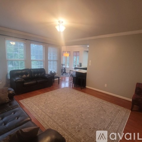 A living room with a black leather couch and a rug.