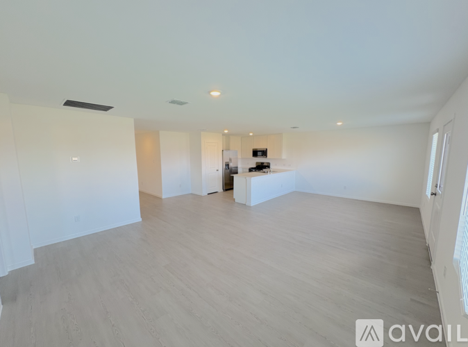 A spacious room with wooden flooring and white walls.