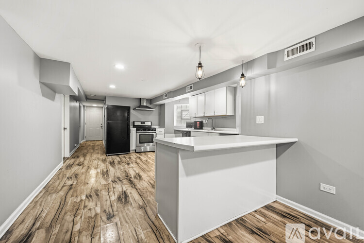 A modern kitchen with wooden floors and white cabinetry.
