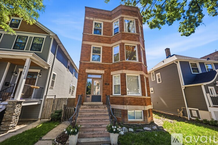 A tall brick building with a staircase leading to the front door.