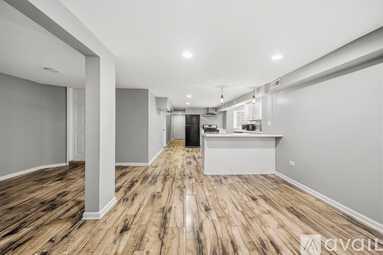 A spacious room with wooden flooring and white walls.
