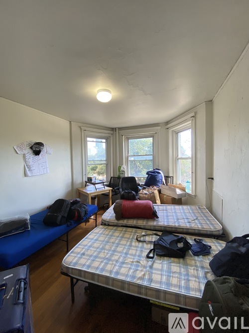A room with two beds and a couch with luggage on it.