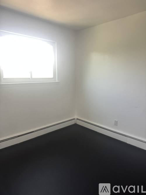 A room with a window and a white wall.