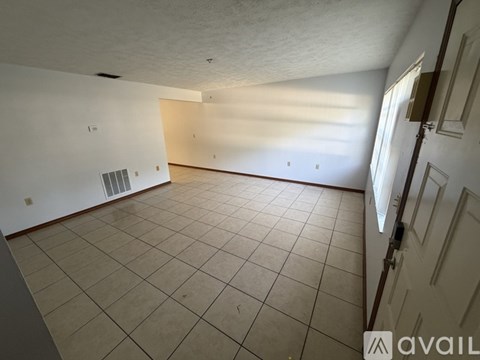 A spacious room with tiled flooring and a door on the right side.