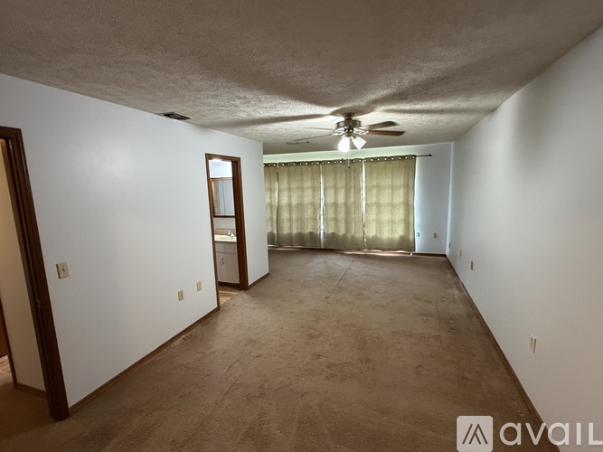 A room with a ceiling fan and a window with curtains.