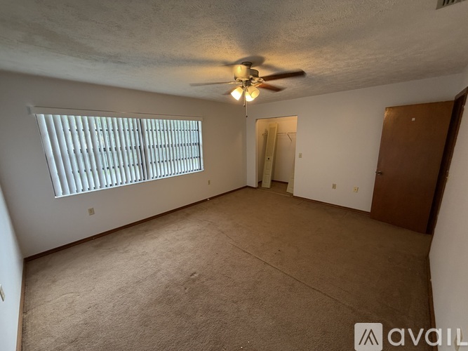 A room with a ceiling fan and a window with blinds.