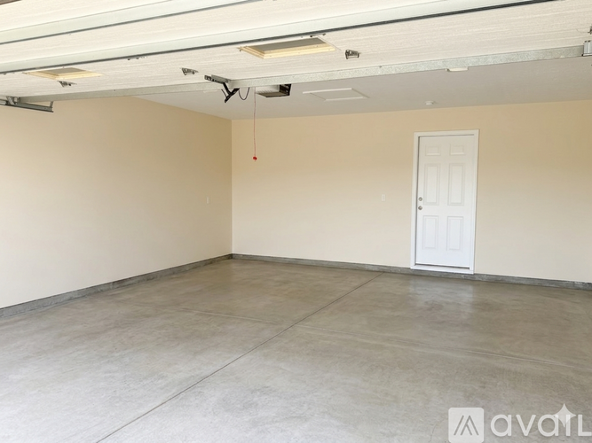 Empty room with a white door and a red object hanging from the ceiling.