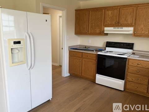 A kitchen with a white fridge, stove, and wooden cabinets.