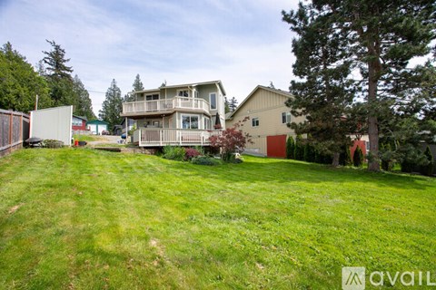 A house with a large lawn and trees in the background.