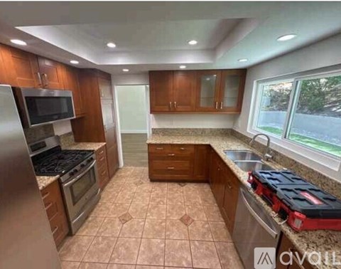 A kitchen with brown cabinets and a tiled floor.