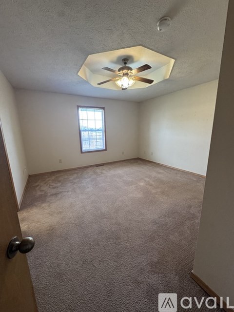 A room with a ceiling fan and a door.