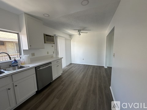 A kitchen with white cabinets and a wooden floor.