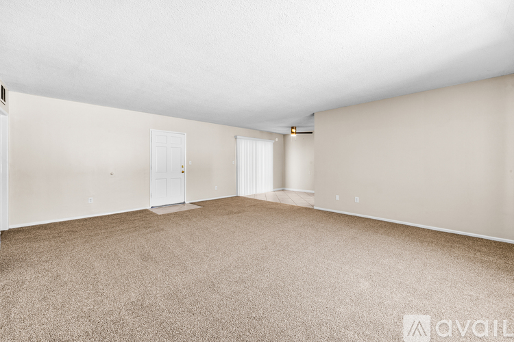 A spacious room with beige carpeting and white walls.