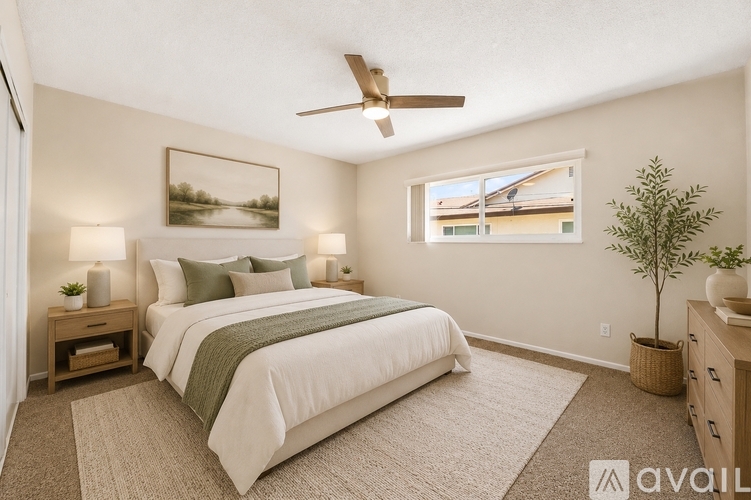 A bedroom with a large bed, a ceiling fan, and a painting on the wall.