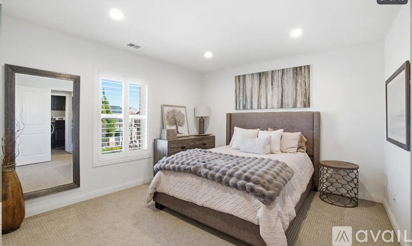 A bedroom with a large bed and a mirror on the wall.