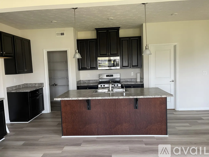 A kitchen with a dark wood island and black cabinets.