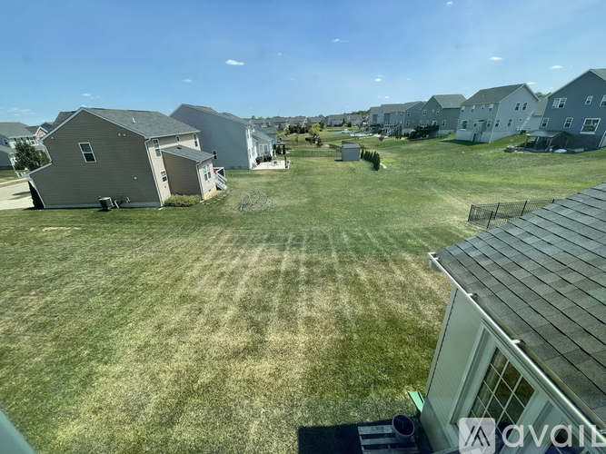 A grassy field with a house and a fence in the foreground.