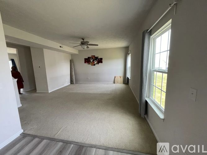 A spacious room with a carpeted floor and a ceiling fan.