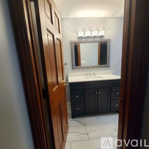 A bathroom with a sink, mirror, and wooden door.
