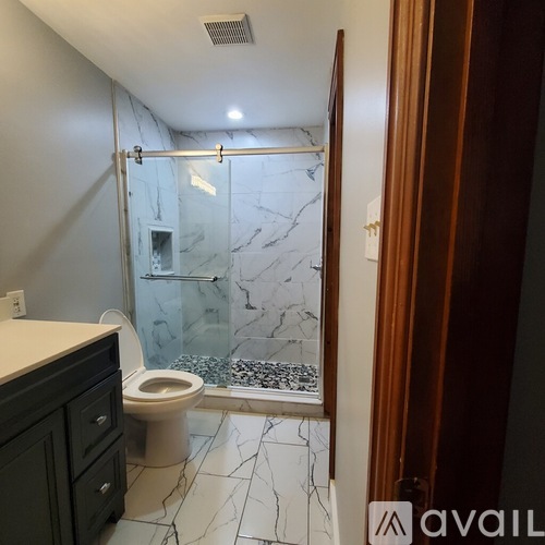 A bathroom with a marble floor and a walk-in shower.
