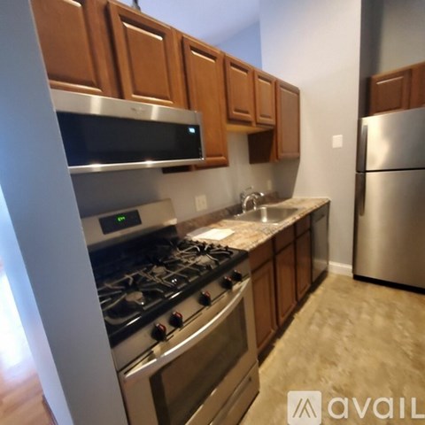 A kitchen with wooden cabinets and a stainless steel refrigerator.