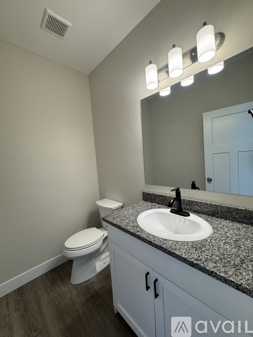 A bathroom with a toilet, sink, and mirror.