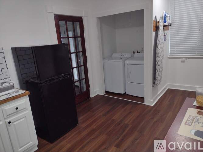 A kitchen with a black fridge, white oven, and a white washer and dryer.