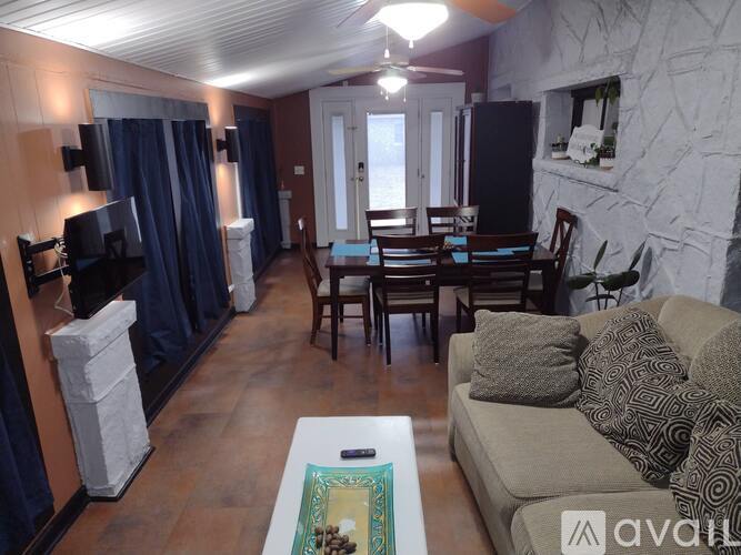 A living room with a couch, chairs, and a television.