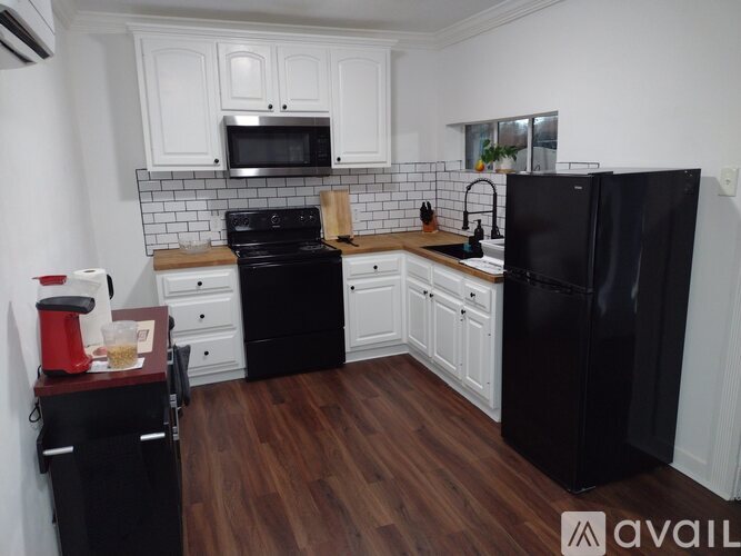 A kitchen with black appliances and white cabinets.