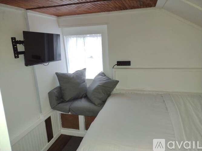 A small bedroom with a grey couch and a flat screen TV mounted on the wall.
