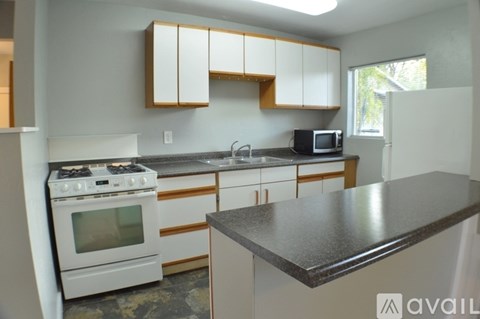 A kitchen with a white stove top oven and a black counter top.