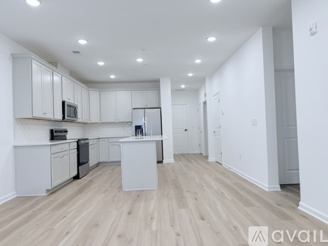 A kitchen with white cabinets and a wooden floor.