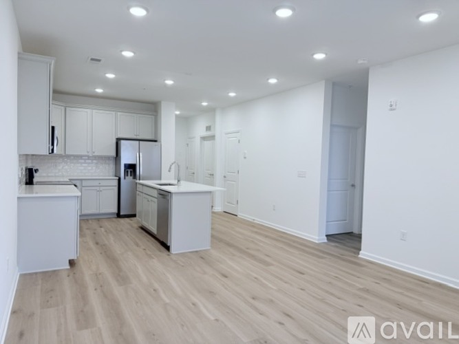 A spacious kitchen with white cabinets and a wooden floor.