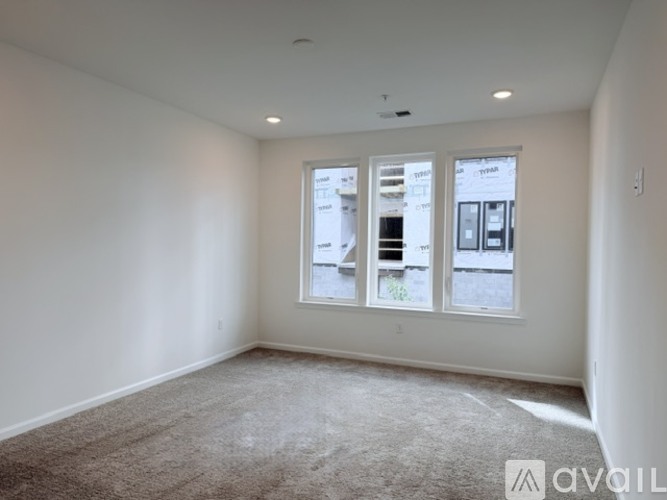 A room with a carpet floor and a window showing a view of a building.