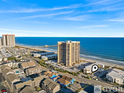 A beachfront area with a tall building and a parking lot.