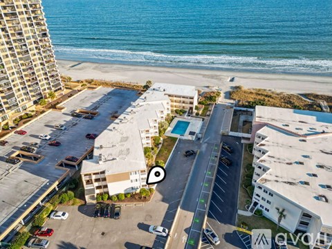 A beachfront hotel with a parking lot and a pool.