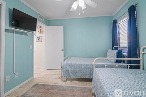 A bedroom with two beds and a television on the wall.
