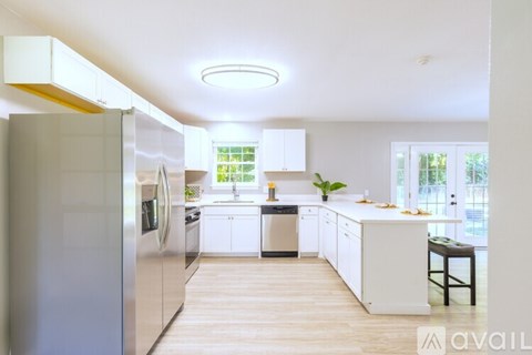 A modern kitchen with white cabinets and a wooden floor.