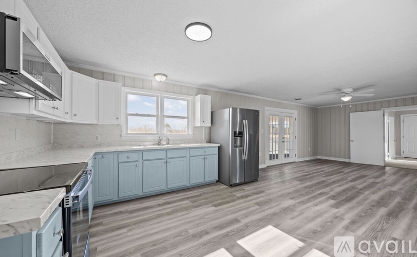 A spacious kitchen with light blue cabinets and a stainless steel refrigerator.