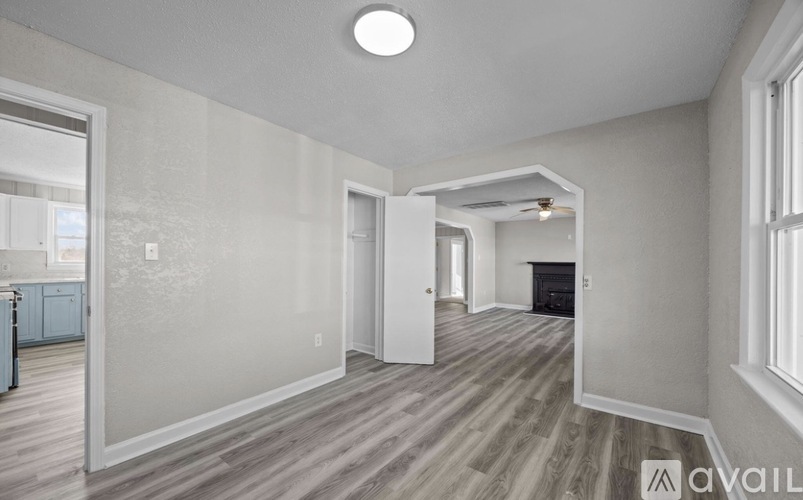 A spacious room with wooden flooring and a fireplace.