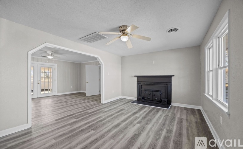 A spacious living room with a fireplace and wood flooring.