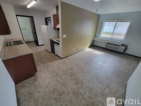A kitchen area with a sink, refrigerator, and a window.