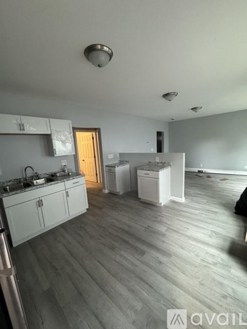 A kitchen with white cabinets and a wooden floor.