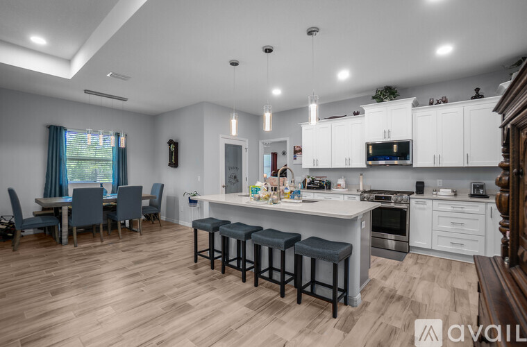 A modern kitchen with white cabinets and a wooden floor.