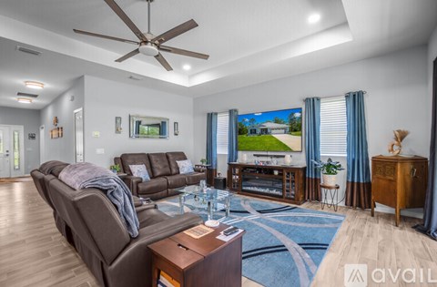 A living room with a brown couch and a ceiling fan.