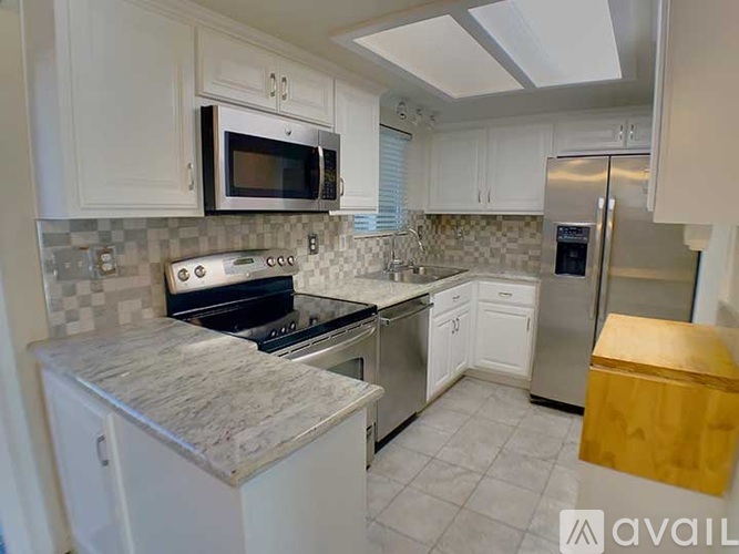 A kitchen with white cabinets and a granite countertop.