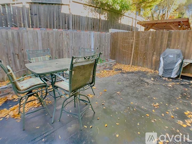 A patio with a table and chairs is surrounded by a wooden fence.