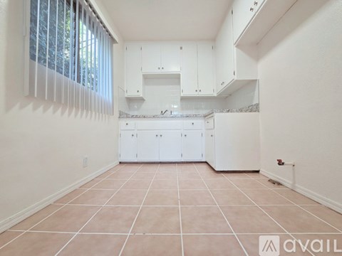 A kitchen with white cabinets and a tiled floor.