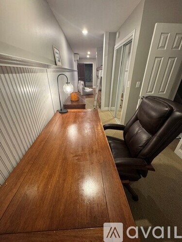 A long wooden table with a black leather chair in front of a white door.