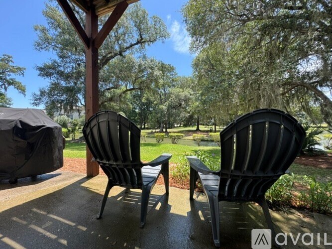 Two black chairs are on a patio with trees in the background.